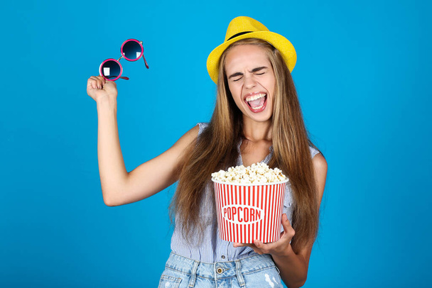 Young girl with bucket of popcorn on blue background - Foto, immagini