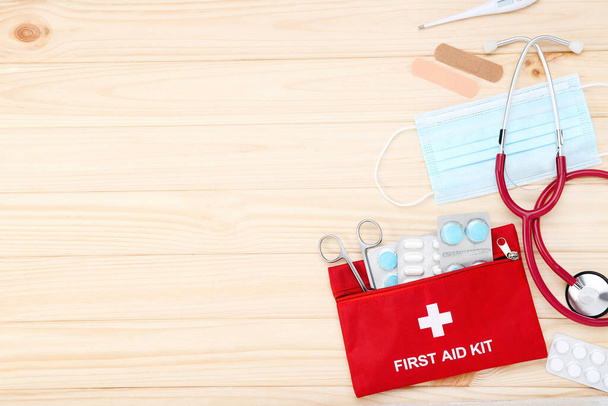 First aid kit with medical supplies on brown wooden table - Zdjęcie, obraz
