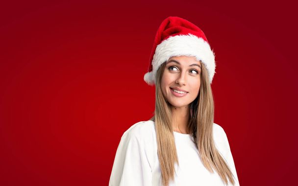 Girl with christmas hat over isolated background laughing and looking up - Photo, image