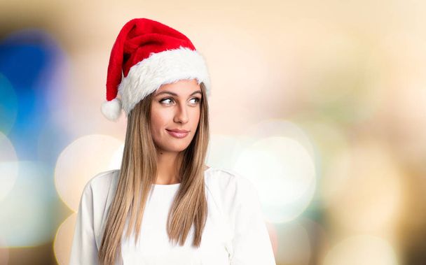 Lány karácsony kalap áll, és nézi az oldalon, mint a koncentrálatlan háttér - Fotó, kép