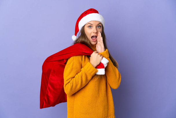 Femme Lithianienne avec chapeau de Noël isolé sur fond violet avec expression faciale surprise et choquée - Photo, image