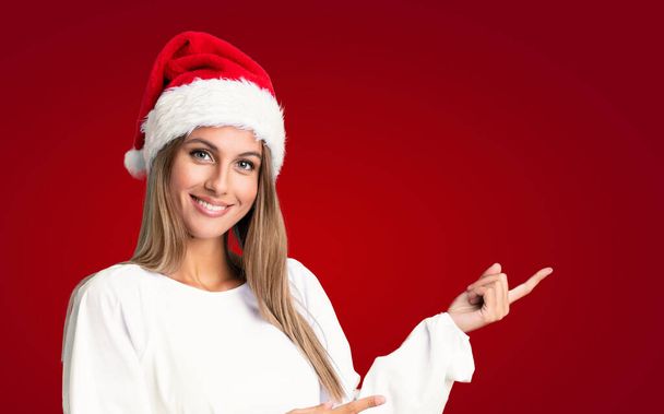 Lány karácsonyi kalap felett elszigetelt háttér mutató ujj oldalra - Fotó, kép