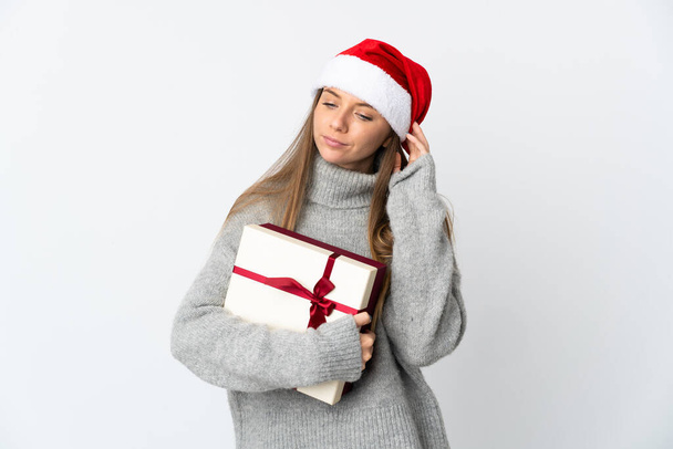 Lithianian woman with christmas hat holding presents isolated on white background having doubts - Photo, image