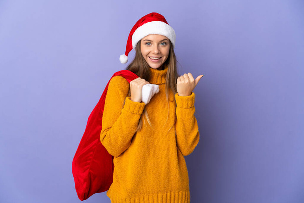 Литовская женщина в рождественской шляпе изолирована на фиолетовом фоне, указывая на сторону, чтобы представить продукт - Фото, изображение