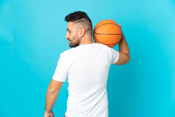 Beyaz adam mavi arka planda tek başına basketbol oynuyor. - Fotoğraf, Görsel