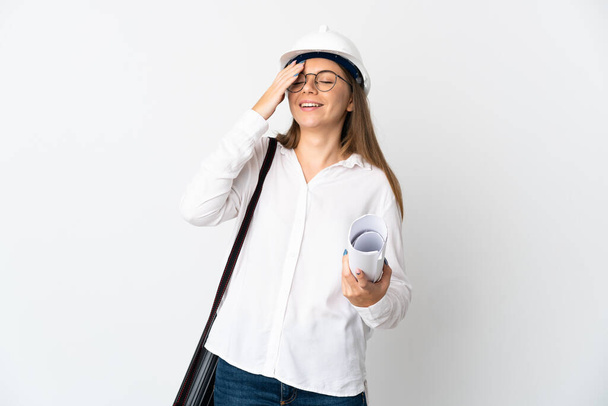 Young Lithuanian architect woman with helmet and holding blueprints isolated on white background smiling a lot - Фото, изображение