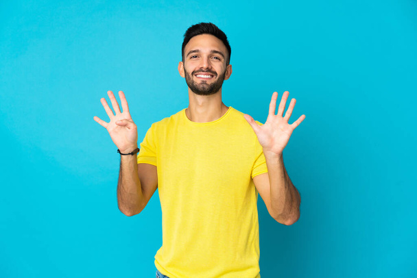 Fiatal fehér férfi elszigetelt kék háttér számolás kilenc ujjal - Fotó, kép