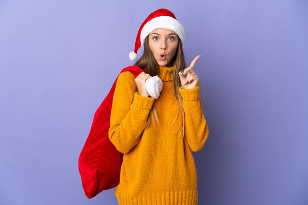 Lithianische Frau mit Weihnachtsmütze isoliert auf lila Hintergrund in der Absicht, die Lösung zu realisieren, während sie einen Finger hebt - Foto, Bild