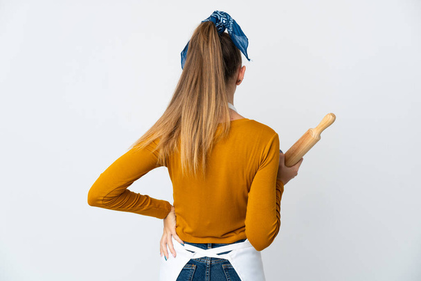 Young Lithuanian woman holding a rolling pin isolated on white background in back position - Foto, immagini