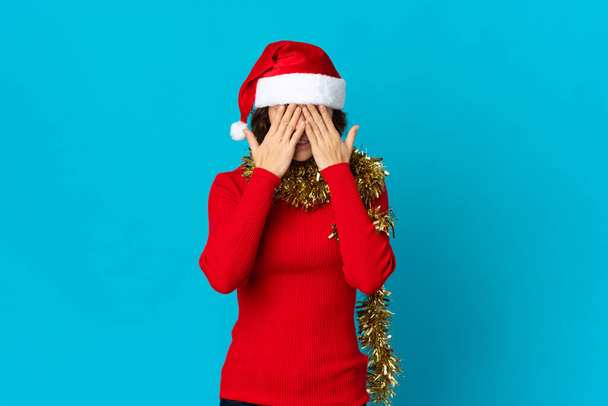 Angielska dziewczyna w świątecznym kapeluszu na niebieskim tle ze zmęczonym i chorym wyrazem twarzy - Zdjęcie, obraz