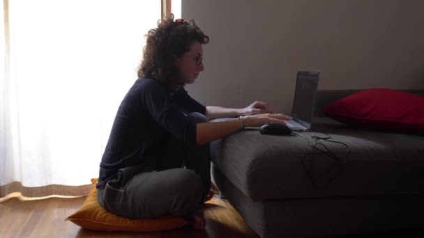 Lockige Frau mit Brille, die während der Covidierung ferngesteuert zu Hause arbeitet - Filmmaterial, Video