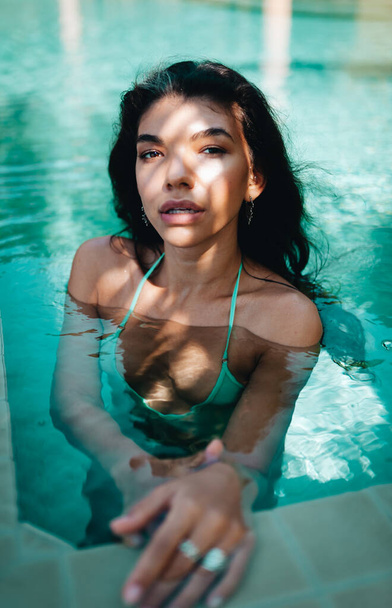 Beautiful long hair female model posing in the swimming pool - Фото, изображение