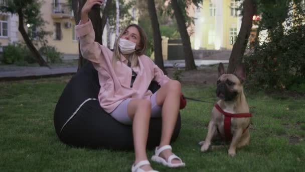 Gyönyörű fiatal nő szelifie vele francia bulldog a parkban - Felvétel, videó