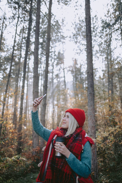 Woman backpacker taking selfie with her cellphone in a forest - Fotoğraf, Görsel
