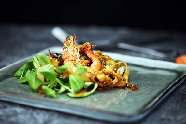 lunch diner maaltijd in een gastronomisch restaurant. voedsel vis elegante gastronomische bord. zee zeevruchten garnalen op donkere plaat - Foto, afbeelding