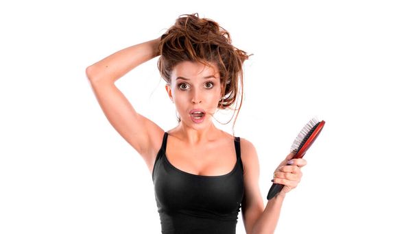 The woman has a problem with hair loss. She stands with a comb in her hand and looks at the camera. Hair health concept - Photo, Image