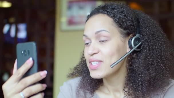 Afroamerikanerin im Kopfhörer unterhält sich online mit einem Freund. - Filmmaterial, Video