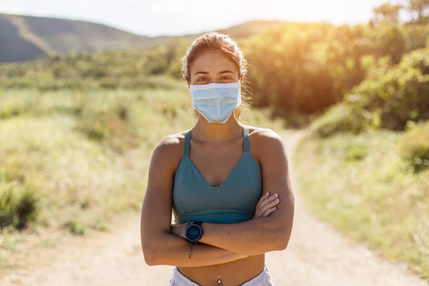 Portrait of motivated fit young female runner wearing face mask on running outdoor workout. Coronavirus health pandemic new fitness lifestyle. - Фото, изображение