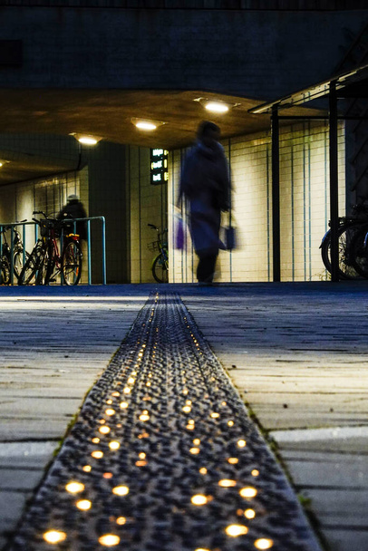 Стокгольм, Швеция Пешеходы в силуэте и освещенная дорожка в пригороде Ульрихала. - Фото, изображение