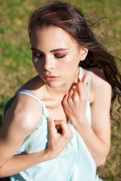 Brunette girl in a turquoise blouse, summer park outdoors - Fotó, kép