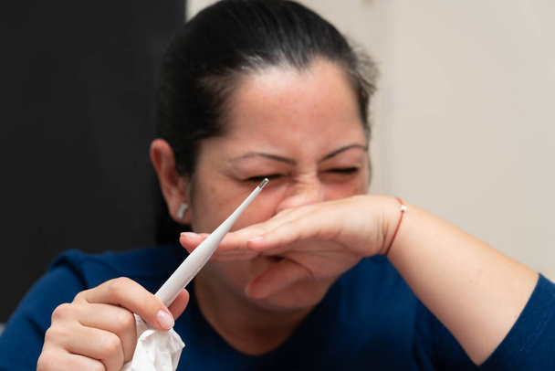 Sick woman having runny nose sneezing as holding thermometer for cold or flu symptom covid19 virus infection concept - Photo, image