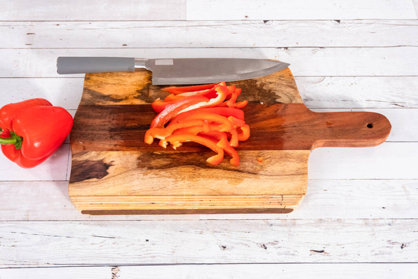 Corte de pimentas vermelhas orgânicas em uma placa de corte de madeira. - Foto, Imagem