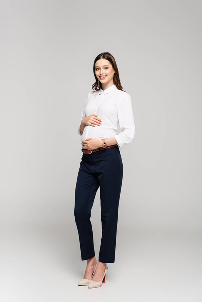 smiling young pregnant businesswoman isolated on grey - Fotografie, Obrázek
