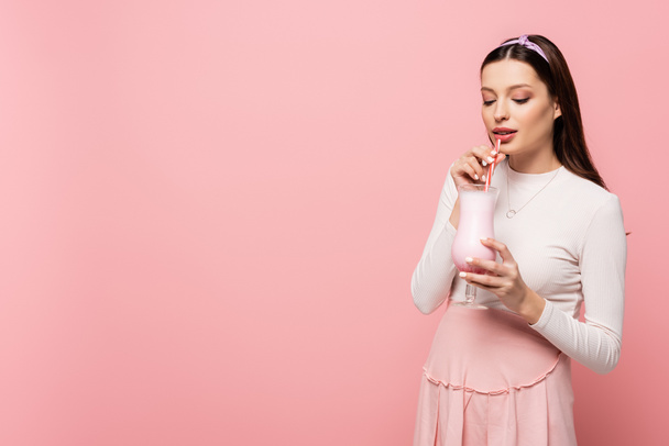 young pretty pregnant woman drinking milkshake isolated on pink - Zdjęcie, obraz