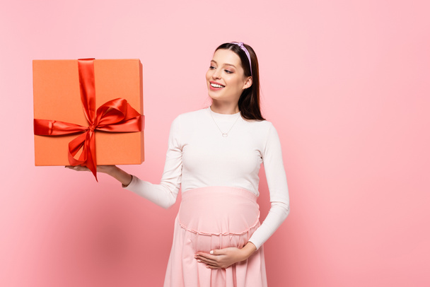happy young pretty pregnant woman with gift isolated on pink - Fotografie, Obrázek