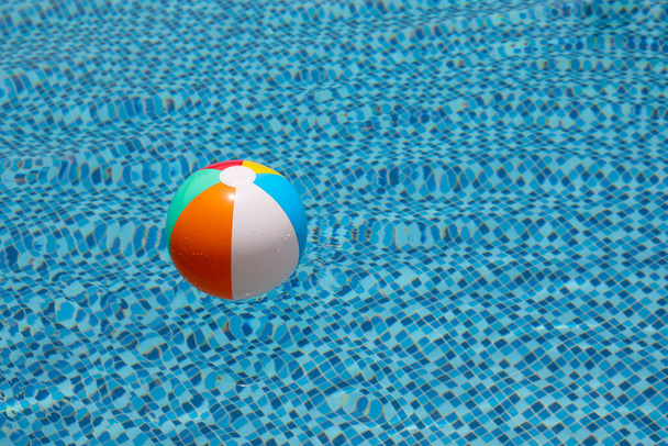 Tengerparti labda a medencében. Színes felfújható labda úszó medence, nyári nyaralás koncepció. - Fotó, kép