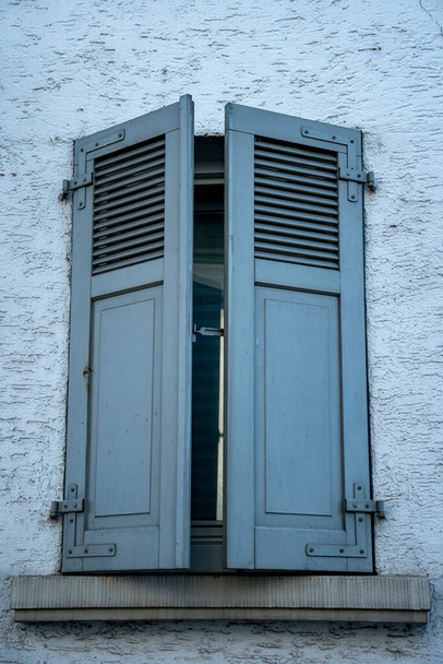 niebieski drewniane okiennice w jednym oknie pół zamknięte - Zdjęcie, obraz