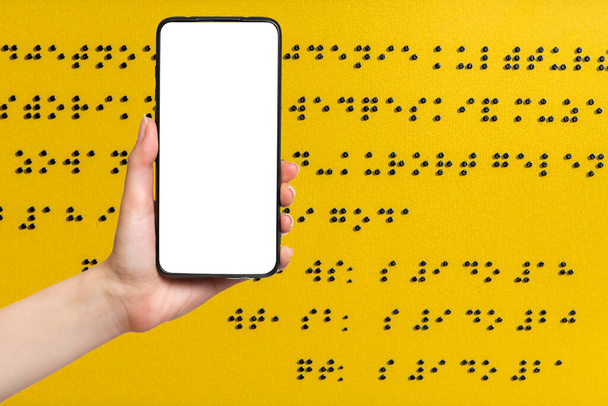 Międzynarodowy Dzień Niewidomych. Dłoń kobiety trzyma smartfona z pustym ekranem. Szykuj się. Pojęcie ślepoty i nauki czytania Braille 'a. - Zdjęcie, obraz