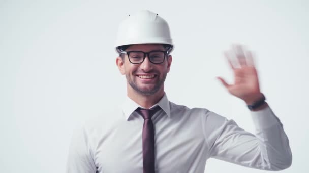 cheerful architect in hardhat and glasses waving hand isolated on white - Filmagem, Vídeo