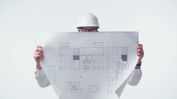 architect in glasses covering face with blueprint and smiling isolated on white - Footage, Video