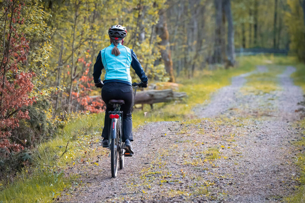 Женщина едет на велосипеде по грунтовой дороге - Фото, изображение