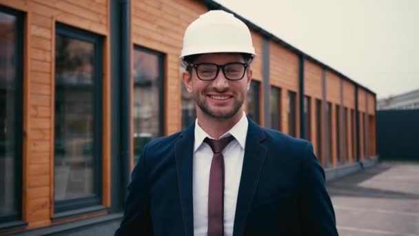 arquiteto feliz em terno e hardhat sorrindo perto do edifício fora - Filmagem, Vídeo