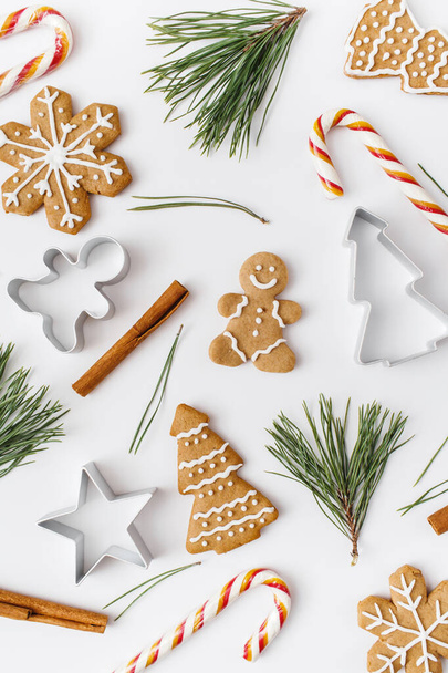 Christmas, winter, new year composition. Pattern made of Fir tree branches, cinnamon sticks, candies, gingerbread on white background. Flat lay, top view - Foto, Bild