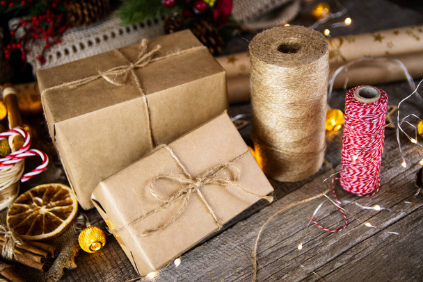 Prezenty w papierze rzemiosła i juta liny na Boże Narodzenie na drewnianym stole. - Zdjęcie, obraz