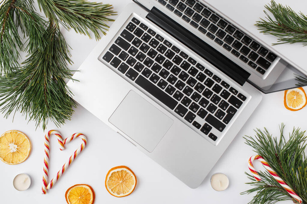 Christmas, winter, new year composition. Home office desk workspace with Fir tree branches, dried oranges, candies, candles on white background. Flat lay, top view - Foto, Imagem
