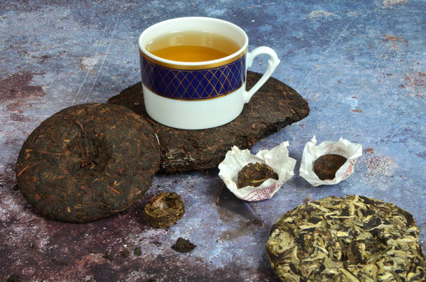 Cup of tea with various Chinese`s puer tea pancakes. Dry Chinese puer tea of high quality. - Photo, Image
