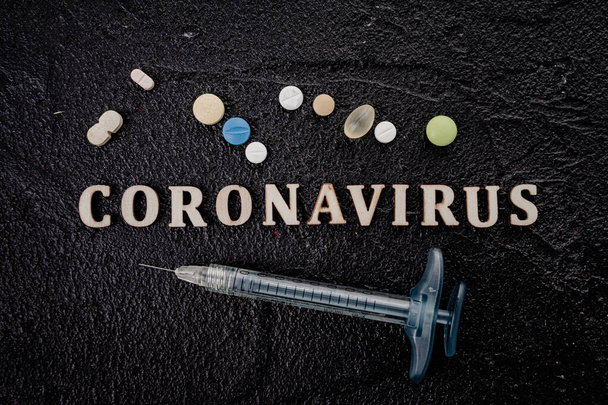 Coronavirus vaccine vial with injection syringe isolated on black background - Photo, image