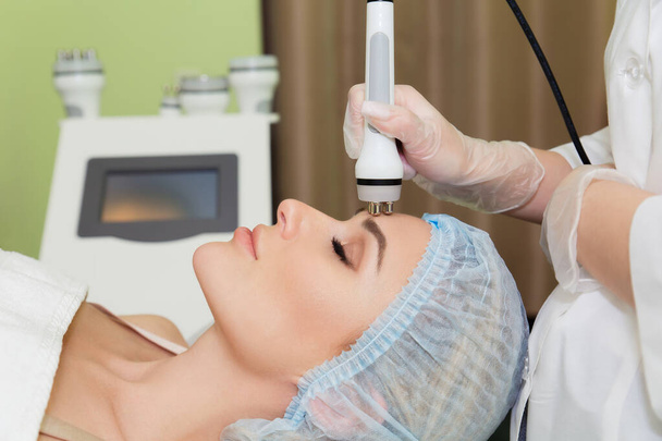 Een jonge vrouw ligt op de RF-lifting procedure voor het gezicht huid aanscherping en gezichtscontour correctie. Close-up. - Foto, afbeelding