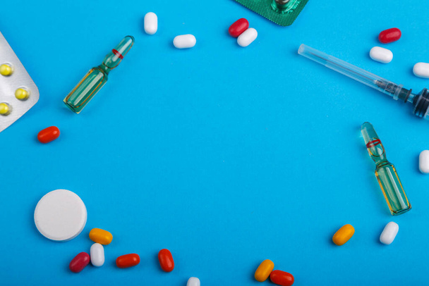 χάπια και φάρμακα σε κυψέλες σε μπλε φόντο και σύριγγα αντίγραφο τόπο. Οριζόντια φωτογραφία. - Φωτογραφία, εικόνα