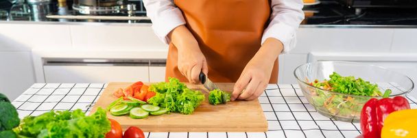 jong aziatisch vrouw is het bereiden van gezonde voedsel groente salade door snijden ingrediënten op snijplank op licht keuken, koken thuis en gezond voedsel concept. - Foto, afbeelding