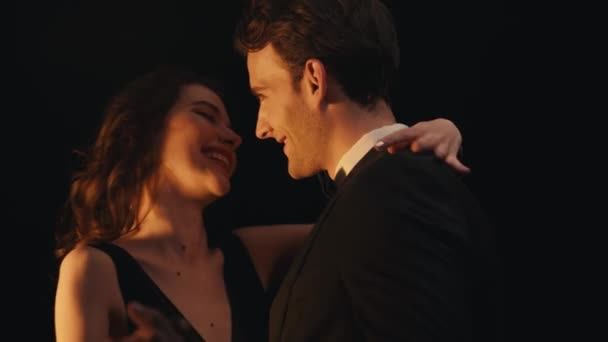 Happy elegant woman laughing while dancing with man in suit isolated on black  - Footage, Video