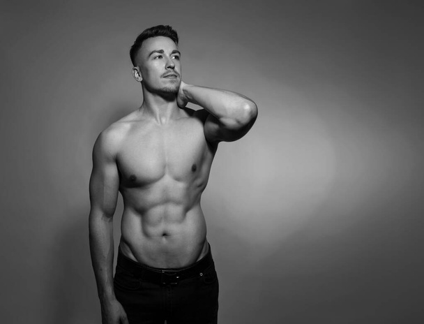 Handsome and fit bodybuilder posing on gray background  - Foto, imagen