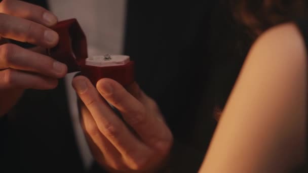 mężczyzna otwarcie przypadku z pierścionek zaręczynowy i całowanie kobieta odizolowany na czarny  - Materiał filmowy, wideo