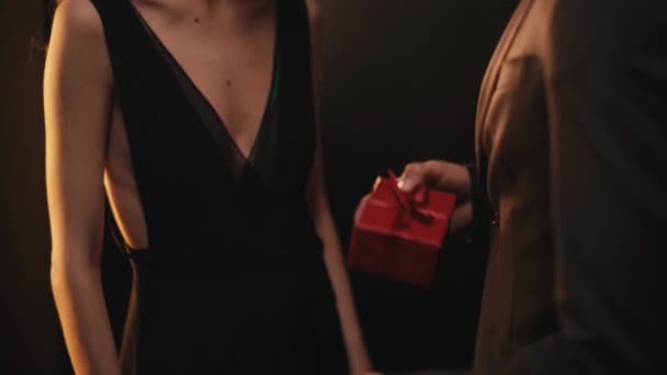 Καλλιεργημένη άποψη της κομψής γυναίκας που λαμβάνει δώρο από τον άνδρα σε μαύρο φόντο - Πλάνα, βίντεο