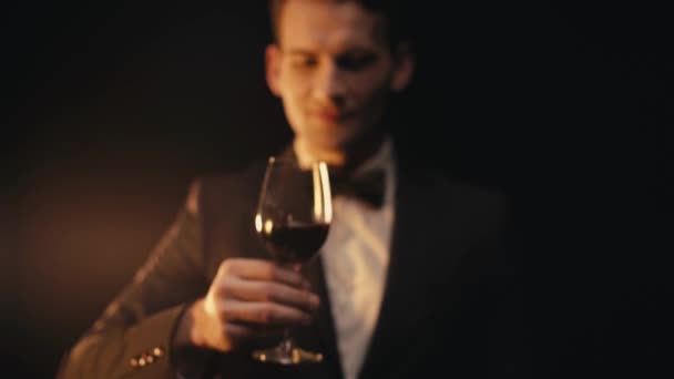 Focus rack di uomo positivo in tuta bere vino su sfondo nero - Filmati, video