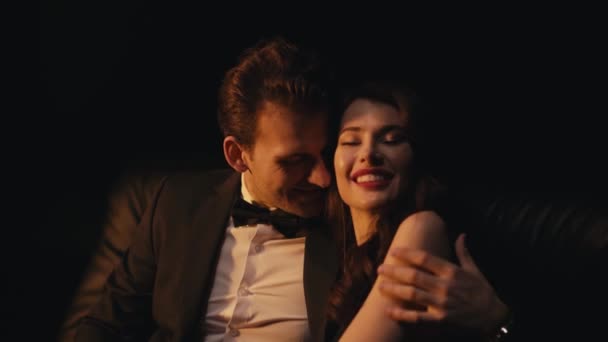 Χαμογελώντας άντρας με κοστούμι αγκαλιάζοντας και φλερτάροντας με κοπέλα απομονωμένη στα μαύρα  - Πλάνα, βίντεο